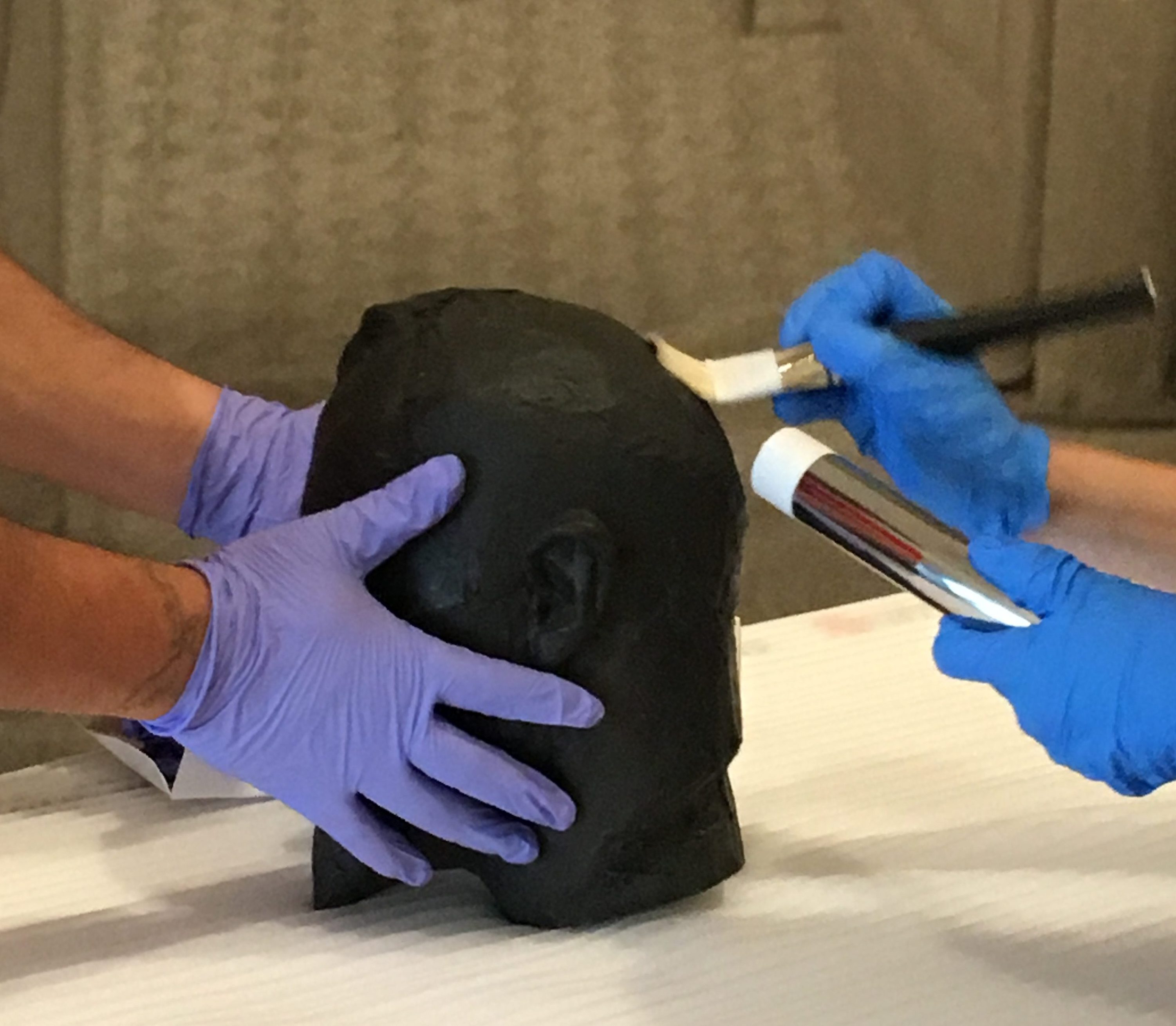Gloved hands preparing a sculpture